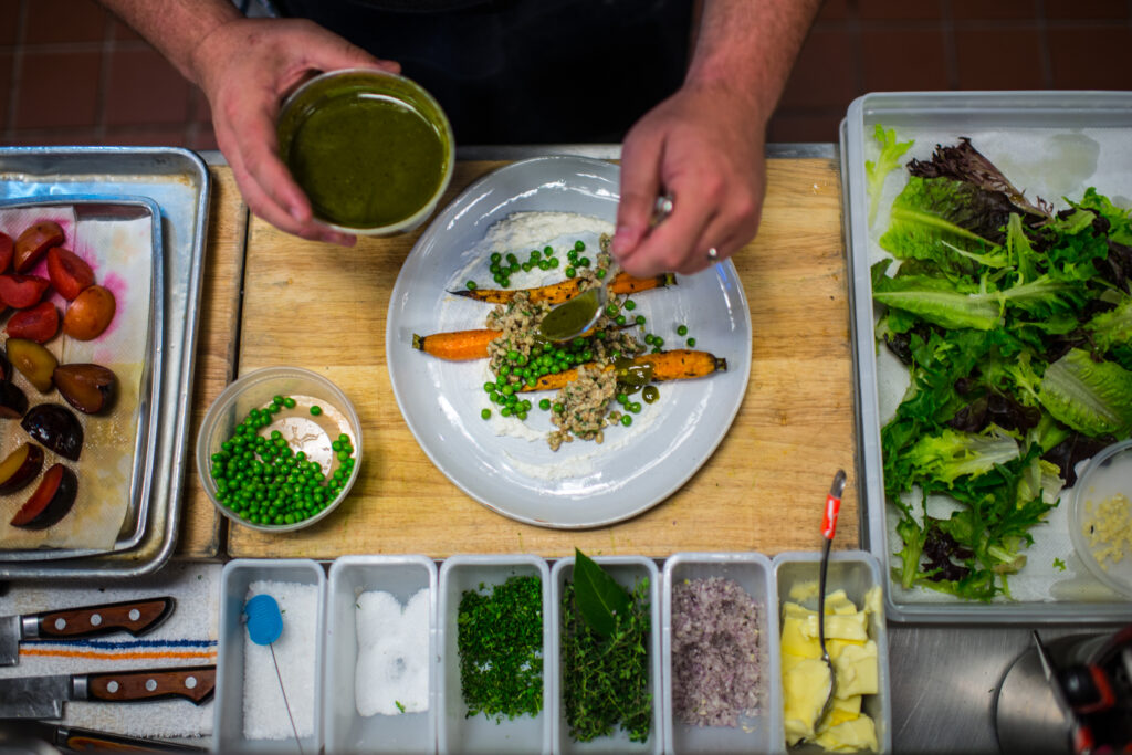 a person creating a plate of food for a catering party with a utensil