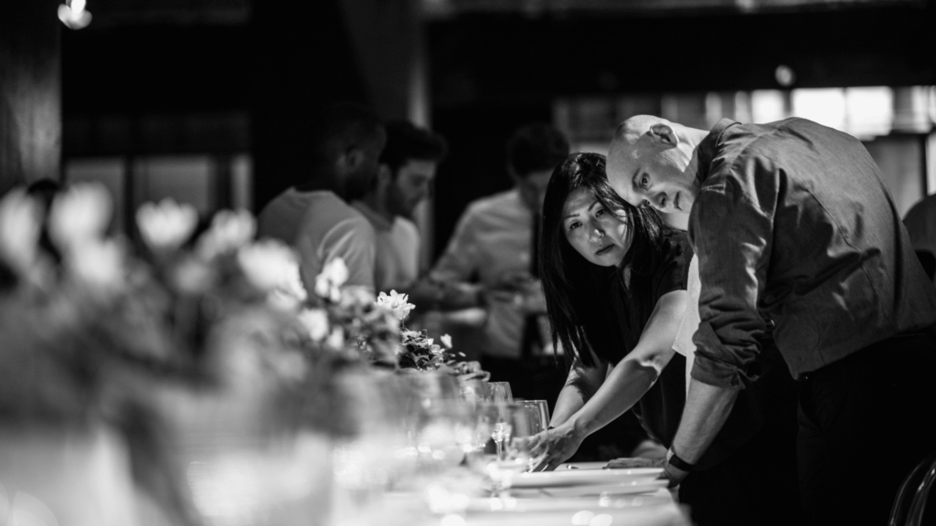 A couple people getting a table ready for a catering party