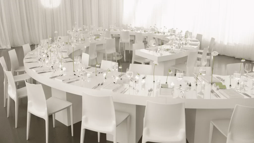 A room full of white tables and chairs set up for a catering event