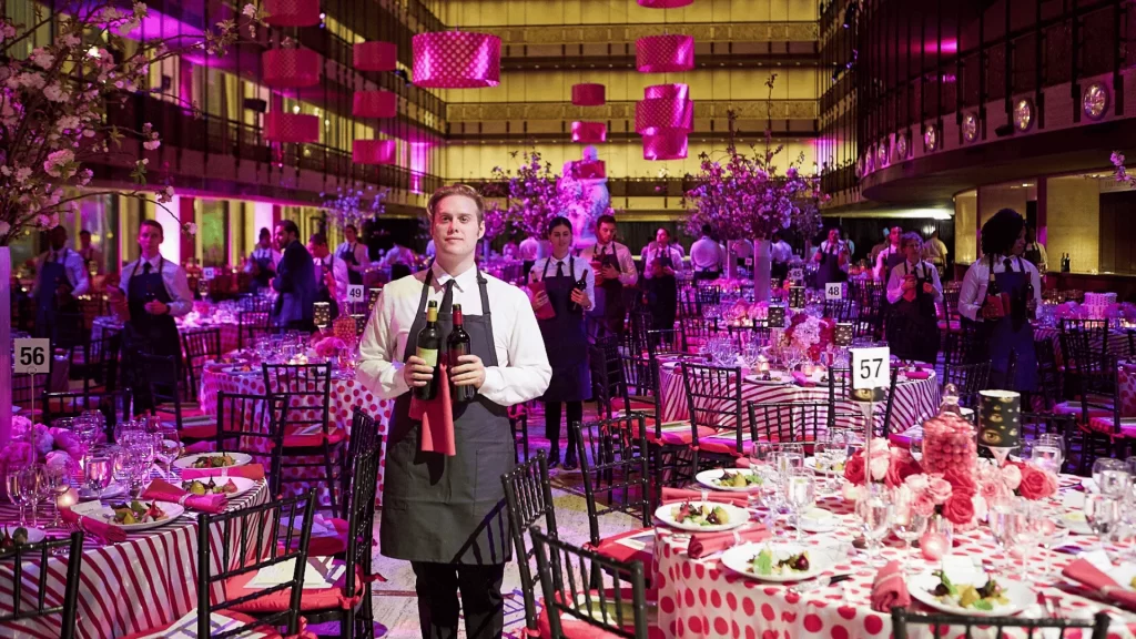 A man holding some wine bottles in a massive catering room