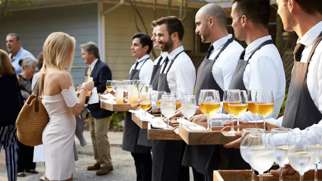 A line of waiters with wine glasses on them